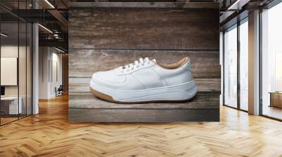 Elegant white eco-leather sneakers with brown sole detail, right, on a wooden background Wall mural