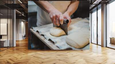 Baker man dividing fresh bread dough with steel scraper in a bakery Wall mural