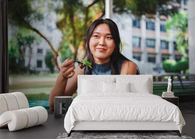 Smiling college student girl eating a healthy salad while taking a break with her friends Wall mural