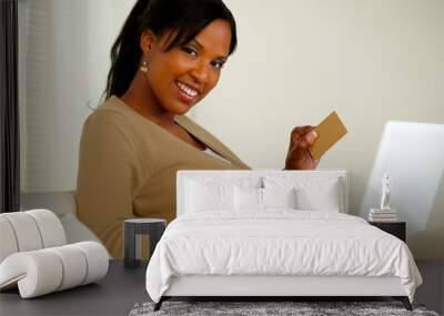 Smiling woman holding a gold credit card Wall mural