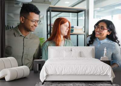 Smiling young multi-ethnic co-working team collaborating, checking documents and doing business working in modern office Wall mural