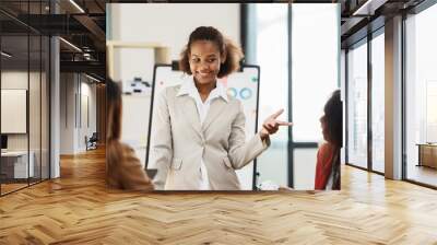 African businesswoman giving presentation on flip chart discussing new marketing research results with executive team in boardroom, black employee reporting about project at meeting Wall mural