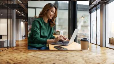 Asian woman working with laptop in coffee shop, business financial concept. Wall mural