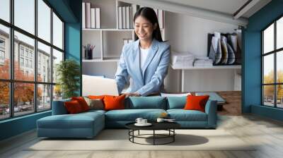 Beautiful Asian businesswoman typing on laptop computer while working in the modern office room. Wall mural