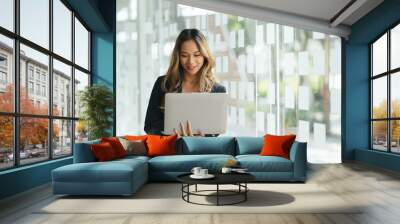 Cheerful young woman holding laptop computer. Pretty lady model with emotionally showing facial expressions in studio, copy space. Wall mural