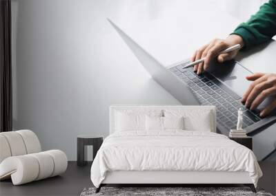 Close-up Businesswoman working online on the white table at office, hands holding pen and typing on laptop keyboard, online job concept. Wall mural