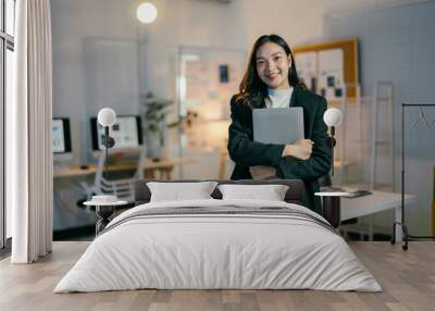 Confident businesswoman in modern office at night, holding laptop, focused and determined, surrounded by technology, symbolizing success and leadership in corporate world Wall mural