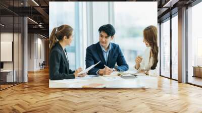 group of four happy young asian corporate people teammates meeting discussing business in office. Wall mural