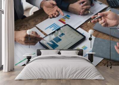 Group of young business people working and communicating while sitting at the office desk together, using tablet to present their concept. Wall mural