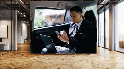 Happy smiling business man typing message on phone while sitting in a car. Wall mural