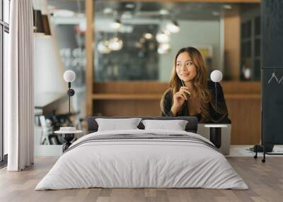 Portrait of dreamy lovely accountant sitting at desk in modern office with interior drinking hot beverage holding cup with tea in hands looking at window enjoying freetime Wall mural