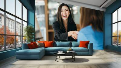 Portrait young Asian woman interviewer and interviewee shaking hands for a job interview .Business people handshake in modern office. Greeting deal concept Wall mural