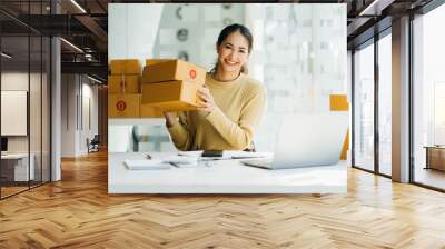 Portrait young attractive asia female owner startup business  work happy with box at home prepare parcel delivery in sme supply chain, procurement, omnichannel commerce online concept. Wall mural