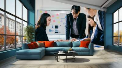 Team of young professionals are gathered around a table, analyzing documents and having a productive discussion about new business strategies Wall mural