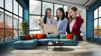 Three women are smiling and celebrating in front of a laptop Wall mural