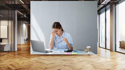 Tired Asian business woman with headache at office, feeling sick at work after a long day with no rest. Wall mural