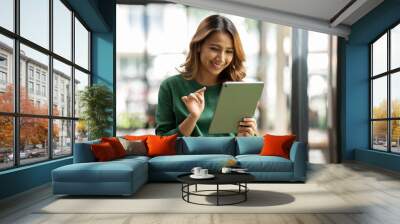 Young asian woman, company worker, smiling and holding digital tablet, standing in her office. Wall mural