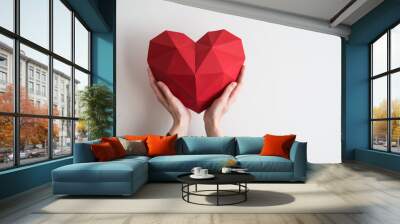 Two female hands holding red polygonal paper heart shape Wall mural