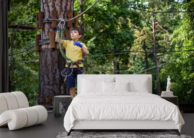 Strong excited young boy playing outdoors in rope park. Caucasian child dressed in casual clothes and sneakers at warm sunny day. Active leisure time with children concept Wall mural