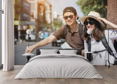 Asian backpack couple tourist holding city map crossing the road - travel people vacation lifestyle concept Wall mural