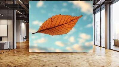 Leaf in the Wind, a solitary leaf dancing through the air against a backdrop of a serene blue sky and fluffy white clouds Wall mural