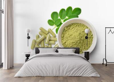 Flat lay (top view) of finely ground dried  Moringa leaves in white bowl with powder capsules and  fresh green  leaves isolated on white background. Wall mural