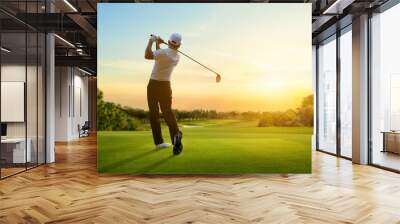 Golfer hit sweeping driver after hitting golf ball down the fairway with sunrise background. Wall mural