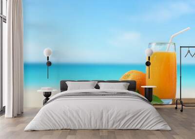 Orange juice on wooden table with tropical beach background. Wall mural