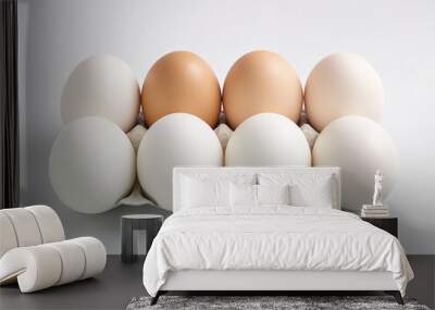 A dozen farm-fresh eggs in hues of white and brown nestled in a cardboard carton, placed on a white background, ideal for culinary themes and healthy diets. Wall mural