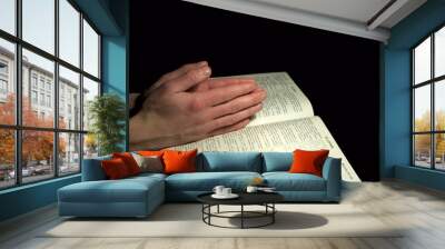 A mans hands clasped in prayer over a  Bible Wall mural