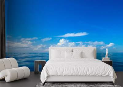 clouds on blue sky over calm sea with sunlight reflection Wall mural