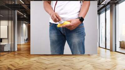 Asian man holding banana representing men's penis with stethoscope on white background, Sexual dysfunction concept Wall mural