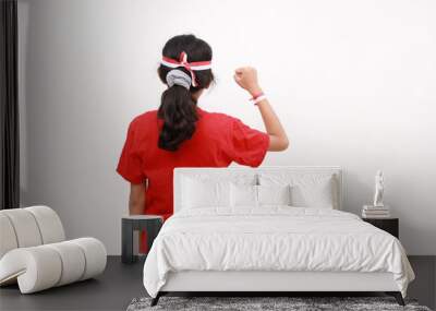 Back view of a young Asian girl with a successful gesture wearing red white flag ribbon isolated by white background. Indonesia's independence day concept. Wall mural