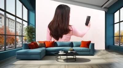 Back view of young asian girl standing while using a cell phone. Isolated on white background Wall mural