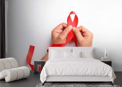 Close up photo of woman's hand holding red ribbon over white background with copyspace. Aids day concept Wall mural