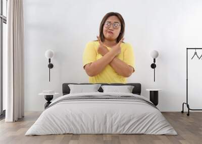 Confused young Asian woman with long dark hair points sideways with index fingers chooses between two options dressed in casual t-shirt isolated white background Wall mural