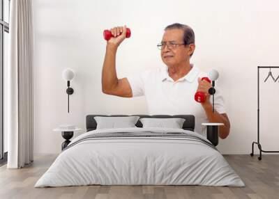 Elderly asian man standing while lifting dumbbells. Isolated on white background Wall mural