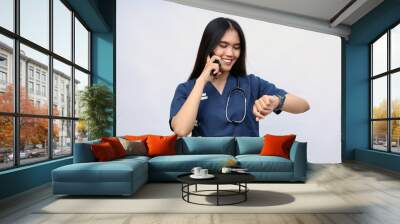 Female doctor with stethoscope talking on mobile phone on white background Wall mural