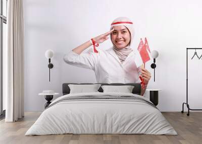 Smiling young Asian muslim woman holding flag indonesian to celebrating indonesian independence day on 17 august and showing respect gesture isolated on white background Wall mural