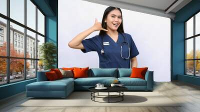 Young asian woman nurse making phone gesture. Call me back sign over white background Wall mural