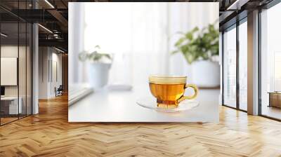 Tea in transparent cup on white desk table with keyboard and plant pot Wall mural