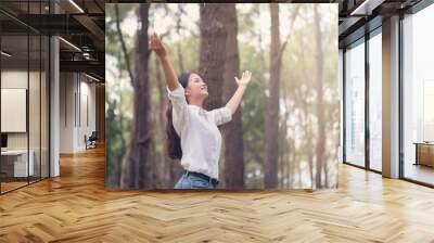 Christian worship with raised hand in pine forest,Happy woman deep breath fresh air in nature breathing clean air. Female enjoying nature and praying to god. Wall mural