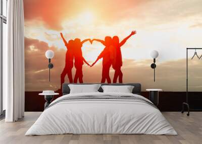 Four female silhouettes hands making a heart shape with sunset b Wall mural