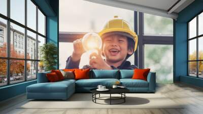 Funny Asian boys hold a light bulb that shines in their hands. Wall mural