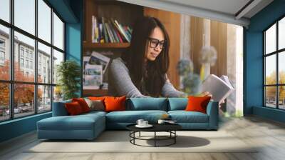 Happy girl reading the Bible in the library cafe. Wall mural