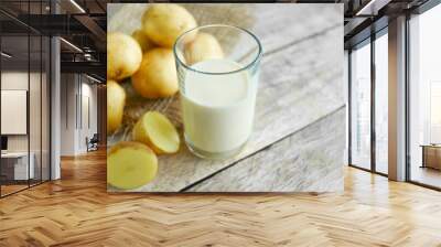 Vegan potato milk in a glass and potatoes on burlap on the wooden background, non-dairy alternative milk,  copy space Wall mural