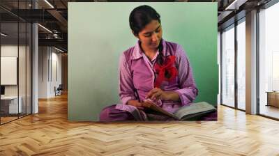 A girl in school uniform reading book while studying at home Wall mural