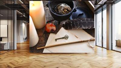 A top view image of two white candle with vintage paper, magic wand, black caldron, and magic spell book on a dark wooden table top.  Wall mural