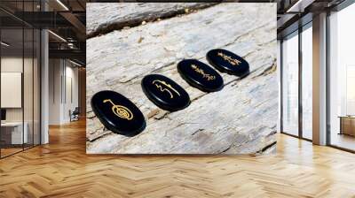 An image of four spiritual healing symbols on black tourmaline crystals and lined up on an old weathered log.  Wall mural