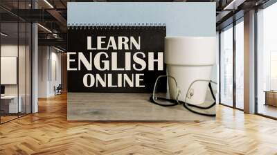 Text LEARN ENGLISH ONLINE . mug, glasses, black notebook for information on the wooden table Wall mural